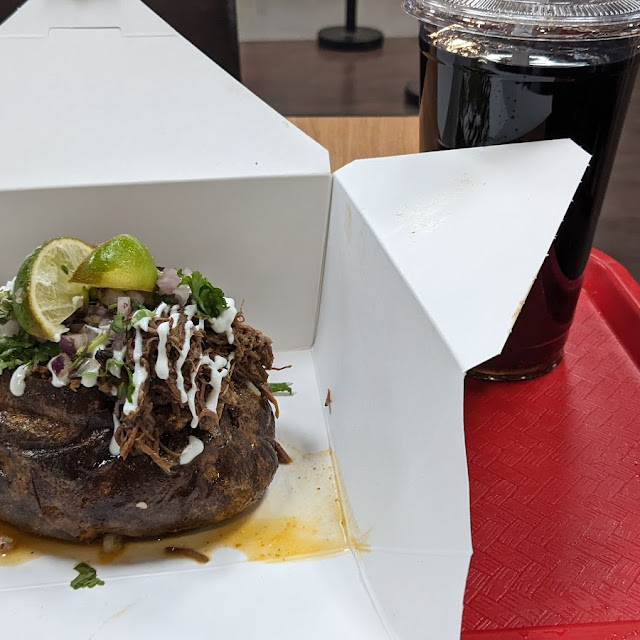 The birria smashburger, a smashed Angus patty with melted cheese and birria, served with thick cut fries