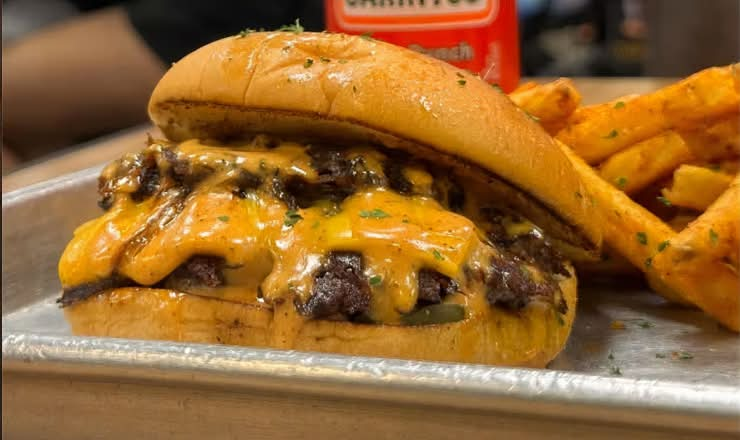The Smash Cheese Burger, a smashed Angus beef patty with melted cheese, pickles, and onions on a potato bun
